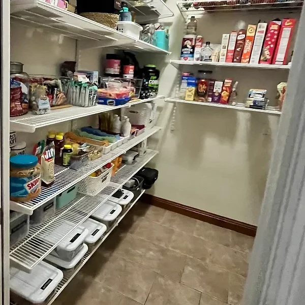 Closer view of pantry shelves with grouped food, baskets and lidded storage containers